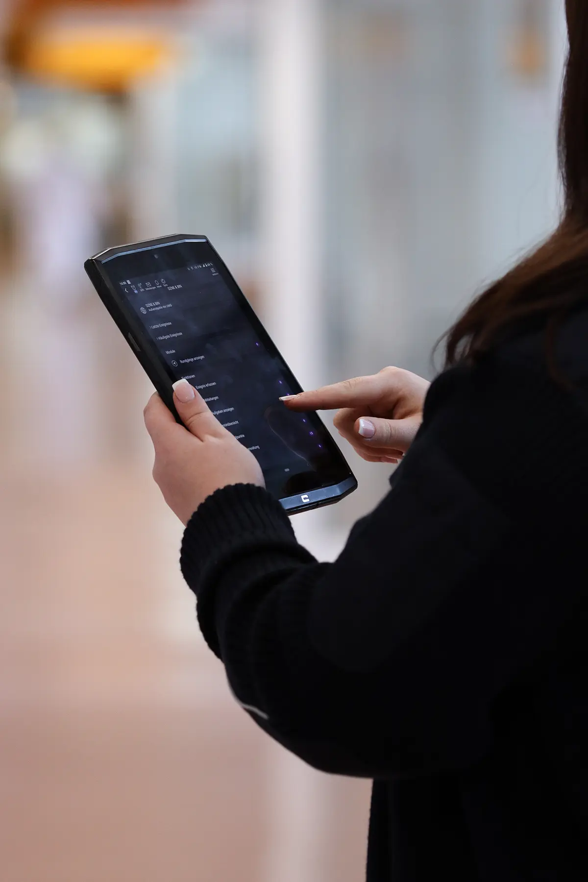 Eine Silhouette einer Mitarbeiterin im Sicherheitsdienst. Sie hält ein Tablet in der Hand, um dort ihre Arbeit zu dokumentieren.