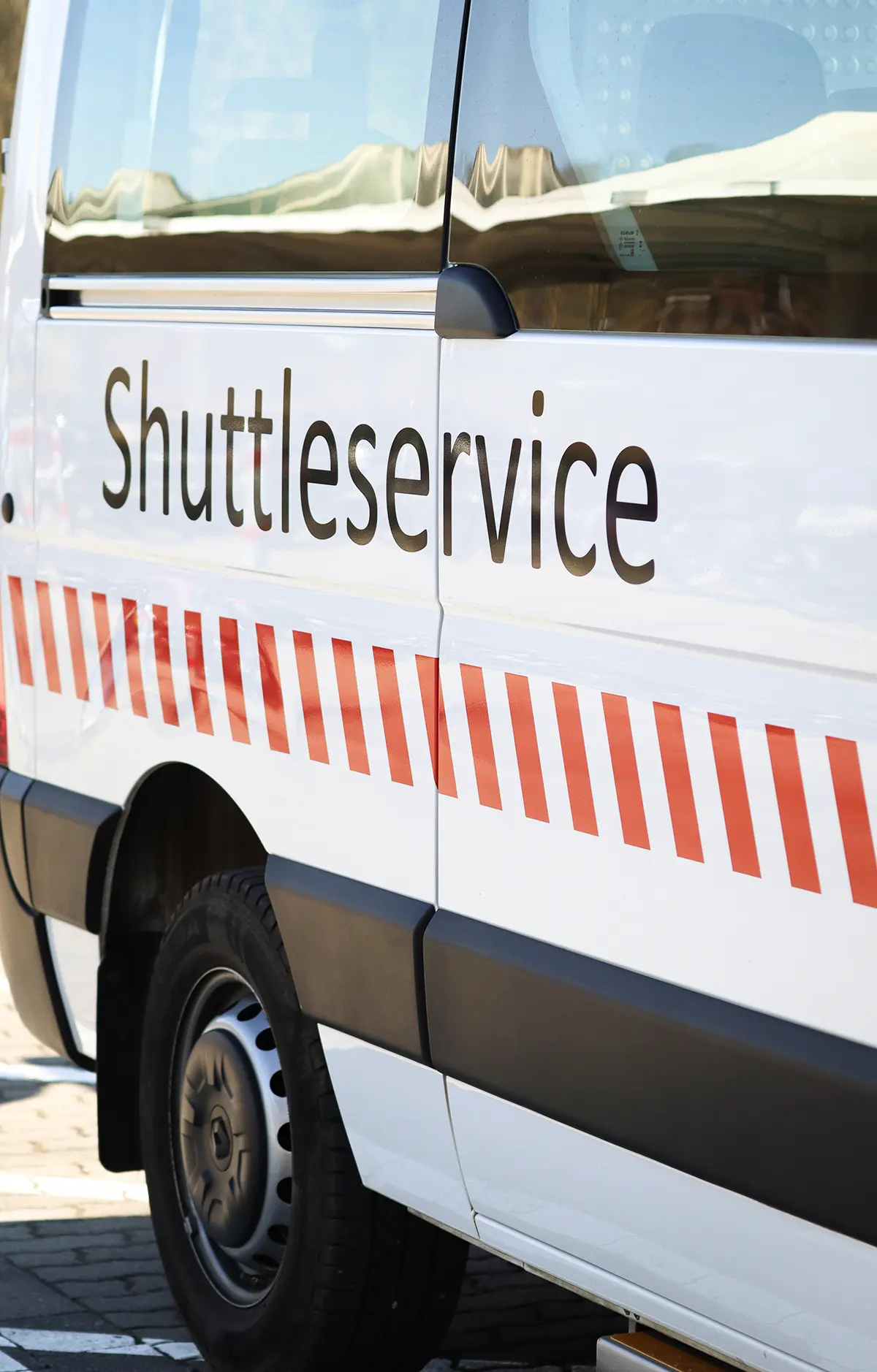 Ein modernes Shuttlefahrzeug mit einer Kennzeichnung für barrierefreien Zugang. Das Fahrzeug ist bereit für die Beförderung von Fahrgästen, einschließlich Menschen mit Gehbehinderung.